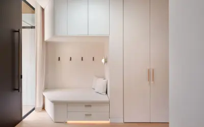 Banquette intégrée avec rangements sous pente, murs clairs, parquet bois.