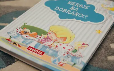 Książka "Wiersze na dobranoc" z dziewczynką śpiącą z misiem i zabawkami.