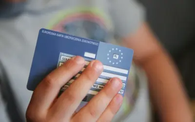 Dziecko trzyma Europejską Kartę Ubezpieczenia Zdrowotnego. To ważny dokument, gdy podróżujesz po Europie. Ekuz co to? To Twoje ubezpieczenie zdrowotne.