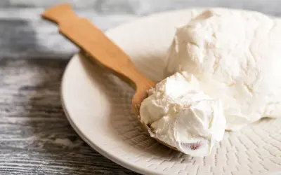 Un cucchiaio di legno raccoglie del cremoso mascarpone da un piatto. Si può congelare il mascarpone per conservarlo più a lungo.