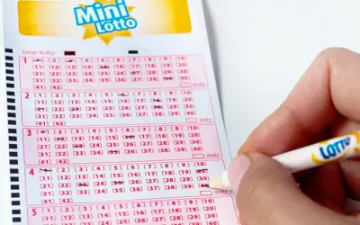 Dłoń z ołówkiem zaznacza liczby na kuponie Mini Lotto. Sprawdzanie lotto centrum wyniki to emocjonujący moment.