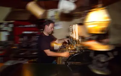 Barista serve birra a un beer fest, con spillatori e bicchieri in movimento.
