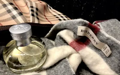 Flakon perfum Burberry Weekend obok szarego szala z charakterystyczną kratą. Idealny zestaw na weekend.