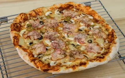 Pyszna pizza z szynką, pieczarkami, oliwkami i ananasem. Idealna na rodzinny obiad, zastanawiasz się ile piec pizze?