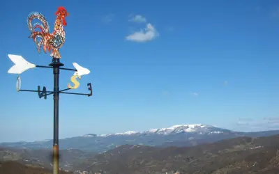 Gallo segnavento su sfondo di montagne innevate in Valmarecchia. Scopri cosa vedere in questa splendida cornice naturale.