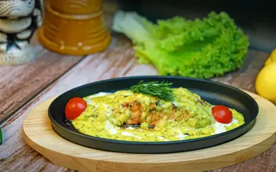 En läcker bit djupfryst lax i ugn, täckt med en krämig sås och dill, garnerad med körsbärstomater och färsk dill.