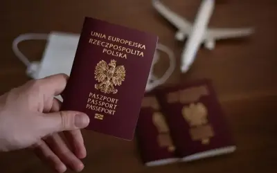 Dłoń trzyma polski paszport. Obok leżą kolejne dokumenty, maseczka i samolot. Zastanawiasz się, ile się czeka na paszport?