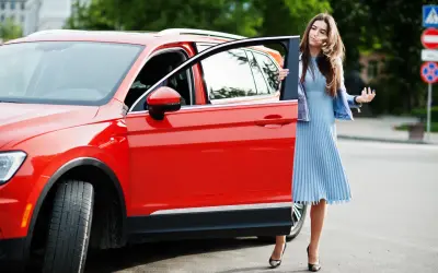 Mujer elegante sale de un monovolumen o SUV rojo brillante.
