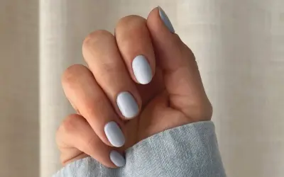 Dłoń z paznokciami w delikatnym baby blue kolorze.
