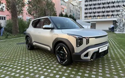 El ev2 kia, un SUV eléctrico plateado, descansa sobre un césped con baldosas cuadradas.