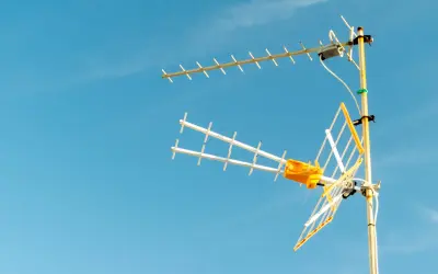 Antena TV z żółtym elementem na tle błękitnego nieba.