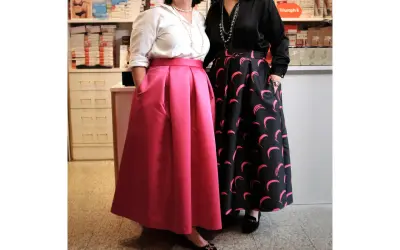 Due donne mostrano diversi tipi di gonne: una rosa a pieghe e una nera con stampa a mezzelune rosa.