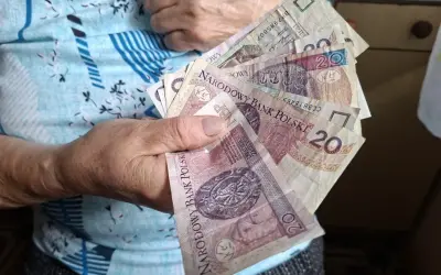 Dłoń starszej osoby trzyma polskie banknoty. To może być część jej emerytury wdowiej, symbolizująca wsparcie finansowe.