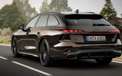 Elegancki Audi Avant w brązowym kolorze jedzie po krętej drodze wśród drzew.