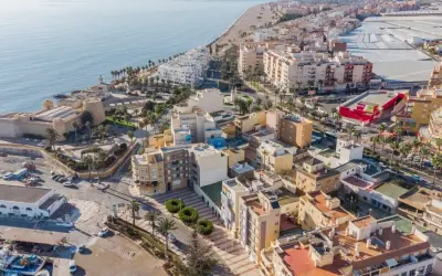 Vista aérea del **centro de Roquetas de Mar**, con el castillo, la playa, edificios residenciales y el mar Mediterráneo.