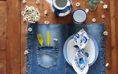 Tovagliette americane fai da te in denim con tasca porta posate, decorate con margherite e un servizio da tavola blu e bianco.
