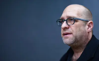 Portret mężczyzny w okularach, łysiejącego, z zarostem. Todd Hido w skupieniu.