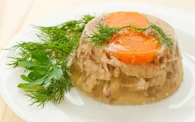 Pyszna galareta z mięsem i marchewką, ozdobiona koperkiem i natką. Idealna na przystawkę, gdy wiesz, jak ugotować galaretę.