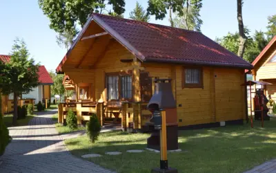 Drewniane domki letniskowe z czerwonymi dachami, idealne na wypoczynek. Sianożęty domki przy plaży czekają na gości.