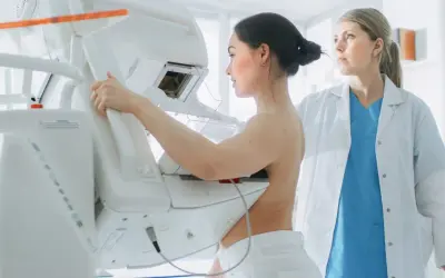 Kobieta podczas mammografii, gdzie zacienienie w mammografii co oznacza jest kluczowe dla diagnozy. Lekarka nadzoruje badanie.