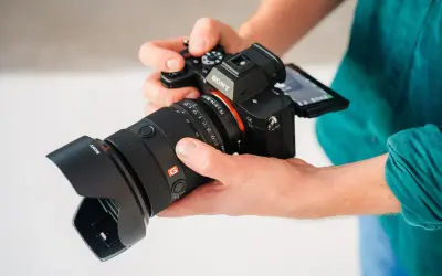Dłonie trzymają aparat Sony a7r5 z obiektywem 24-70mm.