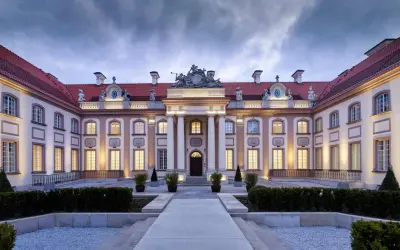Elegancki pałac z czerwonym dachem i oświetlonymi oknami, wieczorem.