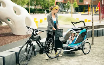 Frau mit Fahrrad und Kinderanhänger, bereit für eine Ausfahrt. Sie genießt das Fahrrad fahren, auch in der Schwangerschaft.