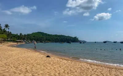 Piękna plaża i turkusowe morze, idealne na wietnam wakacje. W oddali widać łodzie i zieloną wyspę.