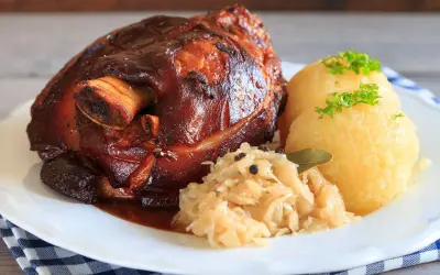 Knusprige Schweinshaxe mit Klößen und Sauerkraut. Ein köstliches Schweinshaxe Rezept für Genießer.