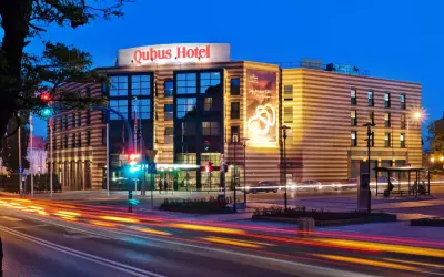 Hotel Qubus Gorzów nocą, z widocznymi światłami samochodów na ulicy i neonem hotelu.