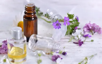 Aromaterapia: amol na co pomaga? Butelki z olejkami i kwiaty sugerują relaks i ukojenie.
