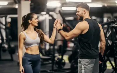 Coppia si dà il cinque in palestra, ispirata da schede palestra con immagini per un allenamento efficace.