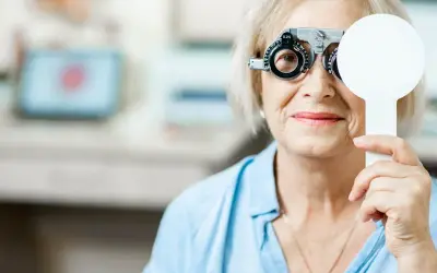 Starsza kobieta z soczewkami próbnymi na oczach, badanie wzroku w celu diagnozy zaburzeń widzenia ICD 10.