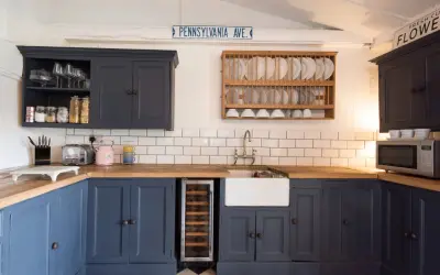 Cocina renovada sin obras: armarios azul marino, encimera de madera, fregadero blanco y suelo de baldosas a cuadros.