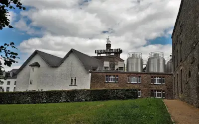 Edificio della Brasserie du Bocq con serbatoi in acciaio inox e un cielo nuvoloso.