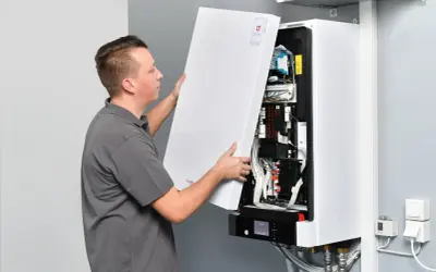 Technik zdejmuje obudowę pieca gazowego dwufunkcyjnego, odsłaniając jego wnętrze.