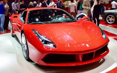 Błyszczący, czerwony Ferrari 488 GTB na wystawie, otoczony ludźmi podziwiającymi jego sportowy design.