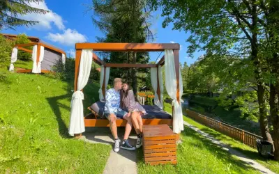 Para spędza romantyczny last minute weekend dla dwojga na łóżku pod baldachimem, otoczona zielenią i strumykiem.
