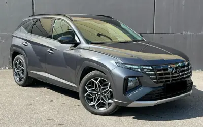 Szary Hyundai Tucson, jeden z najnowszych hyundai suv modele, z charakterystycznymi felgami i nowoczesnym designem, zaparkowany na tle szarej ściany.