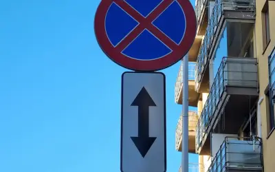 Znak zakaz parkowania ze strzałką w górę i w dół informuje, że postój jest zabroniony po obu stronach drogi.