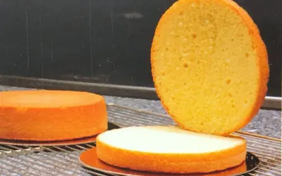 Trois disques de génoise dorée, prêts pour une recette. L'un est coupé en deux, révélant sa texture aérée.