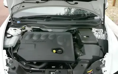 Silnik Volvo V50 2.0D z otwartą maską. Widoczna czarna pokrywa silnika z logo Volvo.