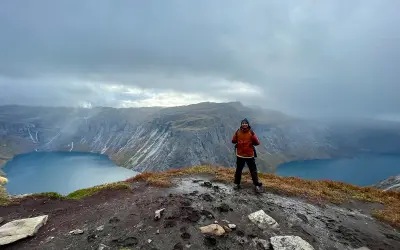 Man på en klippa med en sjö och berg i bakgrunden. En lyckad trolltunga vandring!