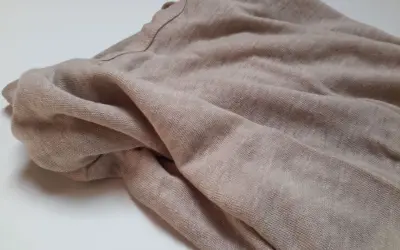 Stoff aus Leinenfasern, weich und atmungsaktiv. Die Textur zeigt, woraus Leinen besteht: natürliche Fasern, die für ihre Langlebigkeit und ihren Komfort bekannt sind.