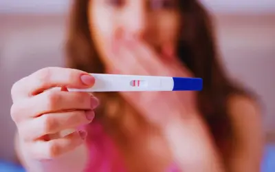 Kobieta trzyma test ciążowy z dwoma kreskami. To może być początek nowej historii, l4 w ciąży.