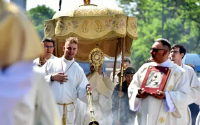 Procesja Bożego Ciała 9 czerwca. Wierni niosą monstrancję pod baldachimem, towarzyszą im księża w białych szatach i kadzidło.