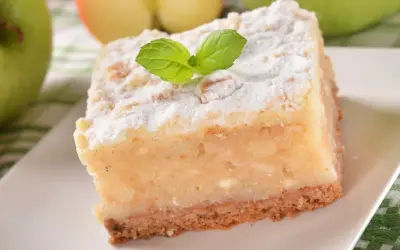 Pyszne, ekspresowe ciasto z jabłkami, posypane cukrem pudrem i udekorowane listkiem mięty. Idealne na szybki deser.