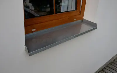 Szary parapet zewnętrzny plastikowy pod drewnianym oknem.