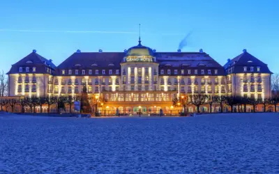 Grand Hotel w Sopocie, jeden z najpiękniejszych hoteli w Polsce, lśni nocą nad piaszczystą plażą.