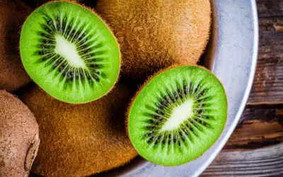 Kiwifruit w misce, przekrojone na pół, ukazujące zielony miąższ z czarnymi pestkami.